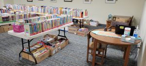 books on tables and in boxes underneath, round wooden table with laptop