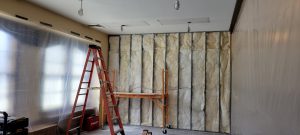 exposed wall studs and insulation, rectangular holes in ceiling with drywall added