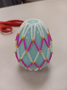 light blue plastic egg with white, pink and yellow beaded net