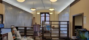 wooden bookcases block off part of the room with plastic draping from ceiling to floor on either side