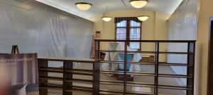 wooden bookcases block off part of the room with two additional bookcases in center covered in plastic and plastic draping from ceiling to floor on either side