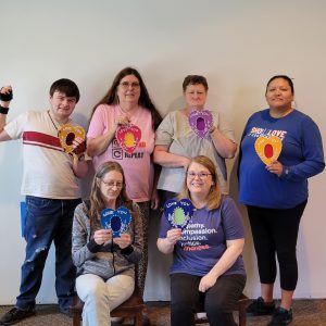 five women and one man holding colorful beaded felt heart picture frames