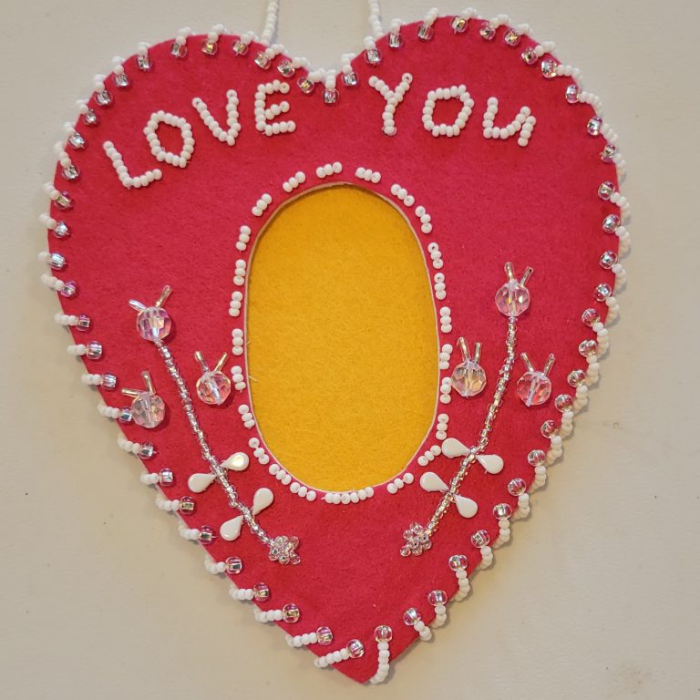 red felt in heart shape with dark yellow felt oval in center and clear and white beaded design