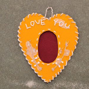 dark yellow felt in heart shape with maroon felt oval in center and clear and white beaded design