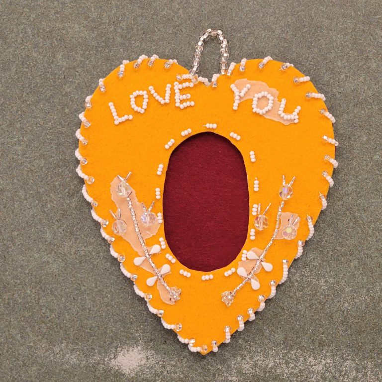dark yellow felt in heart shape with maroon felt oval in center and clear and white beaded design