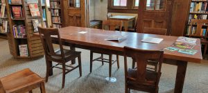 wooden table with 5 chairs and round silver outlet in floor underneath