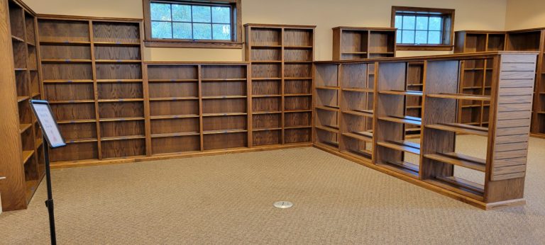 empty bookshelves with open floor area with round silver floor outlet