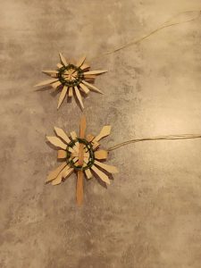 two star or snowflake shaped ornaments woven with dark sweetgrass and black ash splint