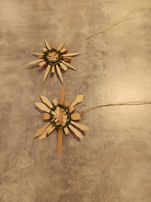 two star or snowflake shaped ornaments woven with dark sweetgrass and black ash splint