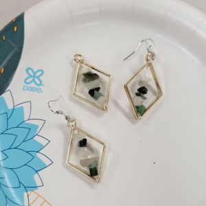 gold diamond bezels with green, black and white crystal chips strung on wire across the center