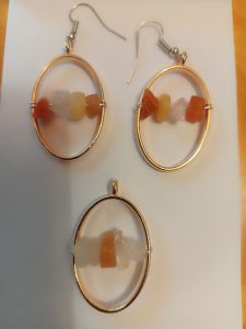 gold oval bezels with orange, yellow, and white crystal chips strung on wire across the center