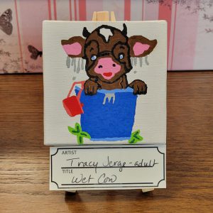 brown cow in blue bucket with water dripping from ears