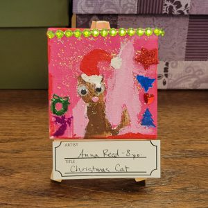 pink background with brown cat with santa hat and Christmas themed sequins