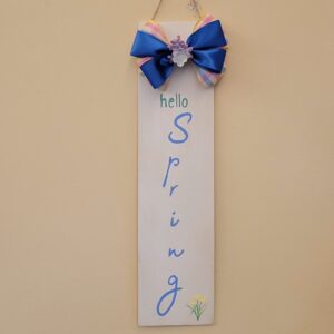 rectangular sign with hello spring and small daffodils painted on and a blue and plaid bow