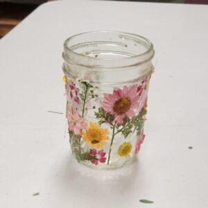 small glass jar with pink yellow and white pressed flowers