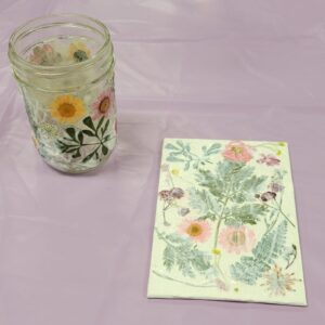 small glass jar with pink yellow and maroon pressed flowers and leaves