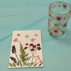 small glass jar and canvas decorated with pink purple and maroon pressed flowers and leaves