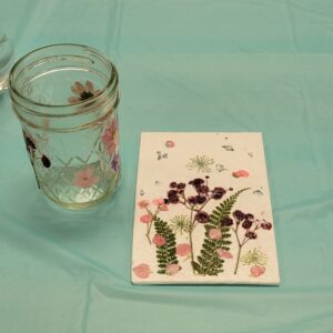 small glass jar and canvas with pink and purple pressed flowers and leaves