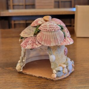 upside down yogurt cup glued to cardboard base with sand walls and shell roof and decor