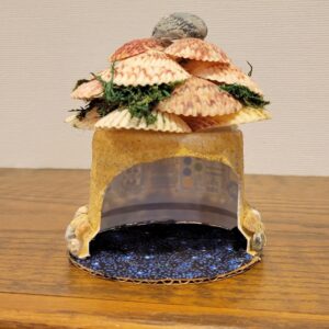 upside down yogurt cup glued to cardboard base with sand walls and shell roof and decor