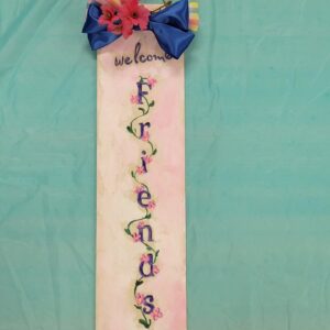 rectangular sign with pink background and welcome friends with pink floral vine painted on and a blue and plaid bow with pink silk flowers