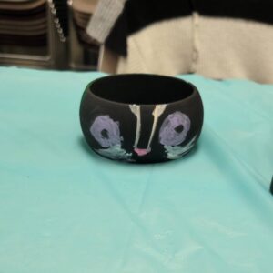 black bangle with skunk face with purple eyes