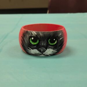 red bangle with black cat face with green eyes