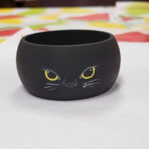 black bangle with small cat face with yellow eyes