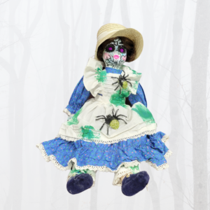 porcelain doll with long blue dress, apron and bonnet with spiders and face painted with cracks and purple eyes