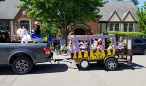 parade float made to look like an RV painted with yellow and black animal stripes and a purple top