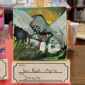 A small painting of a mountainous landscape with houses on display