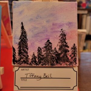 A small painting on an easel shows a forest silhouette against a purple and pink sky.