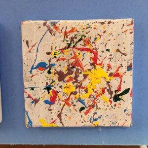 Abstract painting with colorful splatters on a cream canvas.