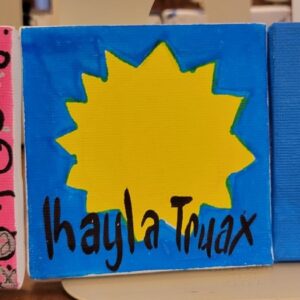 A small canvas with a yellow sun shape on a blue background