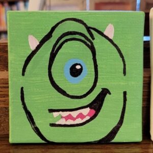 A small canvas painting of a green, one-eyed character with a wide smile
