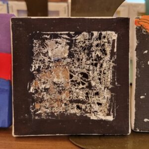 Small canvas painted black with several tears and holes in the center.
