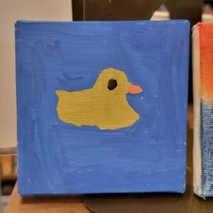 A painting of a yellow duck with an orange beak on a blue background.