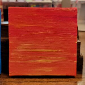 Abstract painting in red, orange, and yellow hues on a small rectangular canvas.