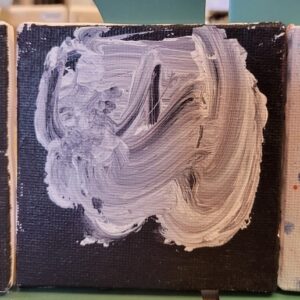 A square canvas with swirling gray and white paint on a black background.