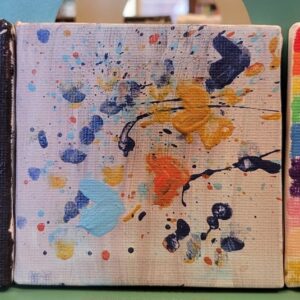 Abstract painting with multicolored paint splatters on a textured canvas.