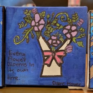 A small canvas painting of a flower vase with purple flowers and a quote, "Every flower blooms in its own time." on a blue background.