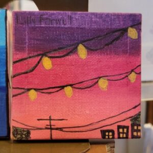 A small canvas painting of a sunset with string lights and silhouettes of buildings.