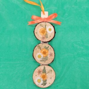 Decorative wooden ornament with pressed flowers and orange ribbon