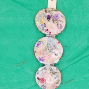 Three wood slices with dried florals glued on them.