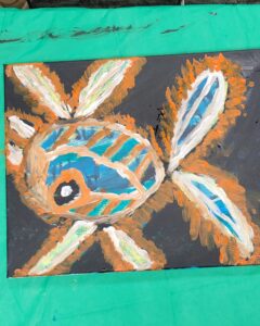 Abstract painting of a fish-like figure with blue, white, and orange colors on a dark background.