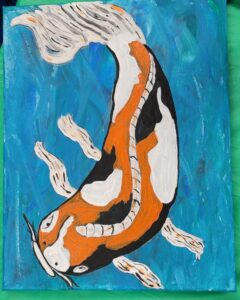 Koi fish swimming in blue water with orange and white patterns.