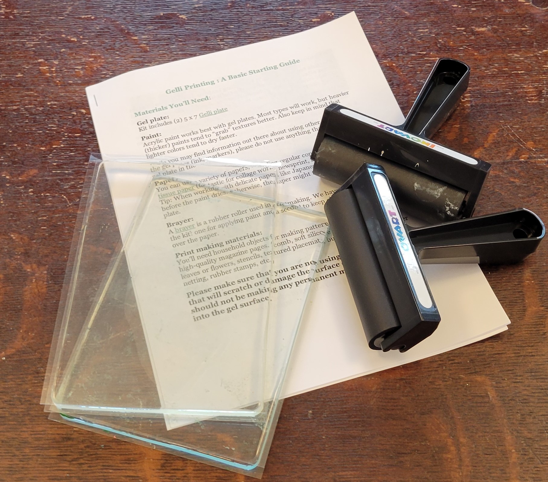 Materials for gelli printing, including printed instructions, brayers, and a gel plate